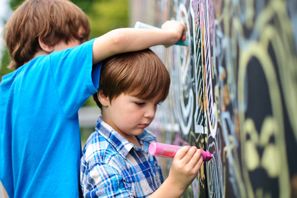 Brothers Ellis (left) and Emmett Early draw with markers on a mural that is part of the G40 Art Summit